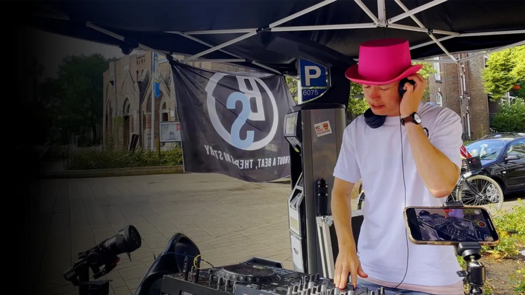 PresidentBrie performing a live tech house DJ set at Snackbar Corry in Nijmegen during the 4Daagse, mixing driving beats as the crowd enjoys the music in an energetic outdoor setting.