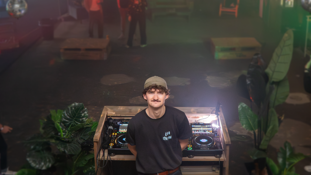Deodaat performing a live DJ set, blending rhythmic percussive elements with groovy disco tracks, creating an upbeat atmosphere on the dance floor.