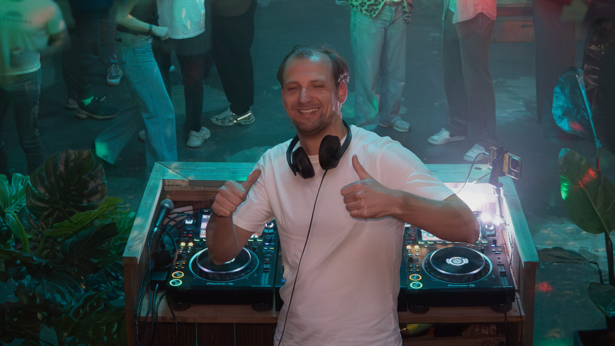 JS Berg performing a live DJ set, mixing vibrant Disco and Afro beats, with a lively crowd dancing under dynamic stage lighting.