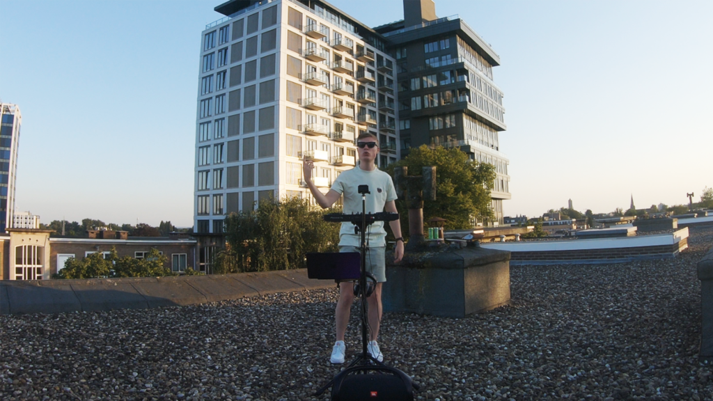 PresidentBrie performing a live rooftop DJ set, transitioning from tech house to techno, with city views in the background and lights enhancing the energetic performance.